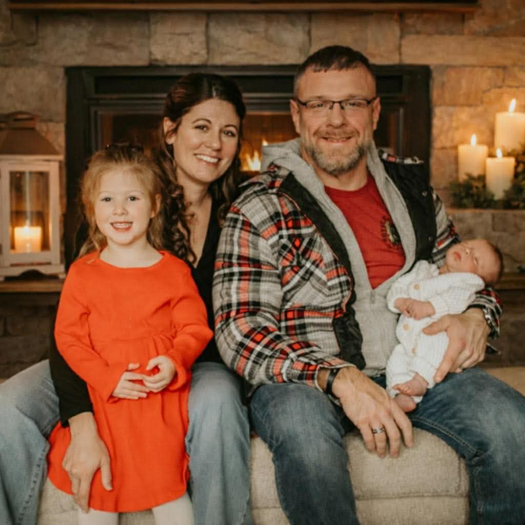Eric Schutte with his wife and two children beside a fireplace